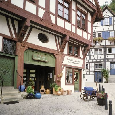 In the foreground an imposing half-timbered house, in which a pottery is housed. in the background there is also a half-timbered house with blue shutters.