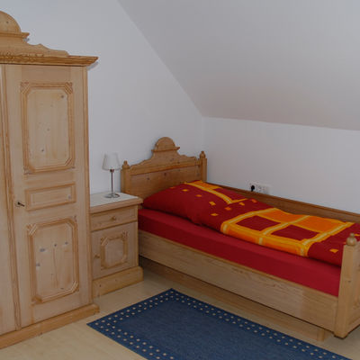 Zimmer mit Holzmöbeln und Einzelbett.