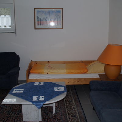Zimmer mit Einzelbett, Tisch und Sofa.
