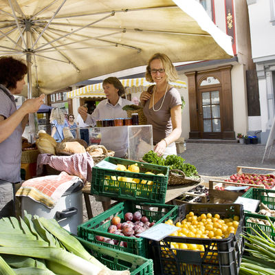 Stand an einem Wochenmarkt mit Obst und Gemüse in der Auslage.