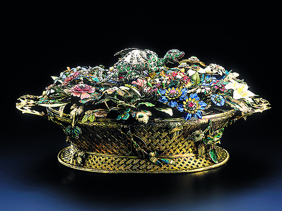 Ein goldener, filifgraner Korb gefüllt mit verschiedenen, fein ausgearbeiteten, bunten Blumen und Blüten, teilweise mit Edelsteinen besetzt.