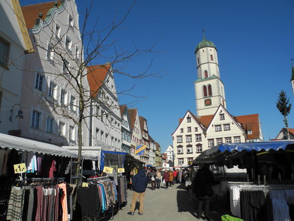 Marktstände säumen den Marktplatz, im Hintergrund ist der Kirchturm zu sehen. 