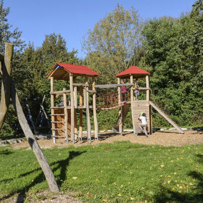 Ein Spielplatz mit einem Klettergerüst und Schaukel aus Holz.