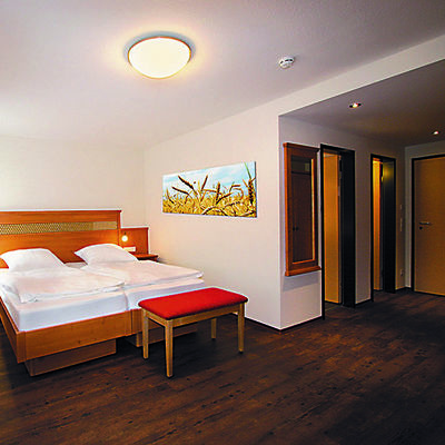 Zimmer mit Doppelbett und Holzfußboden.