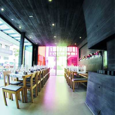 Modernes Restaurant mit Glasfront und festlich gedeckten Tischen.