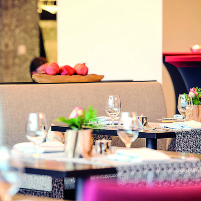 Modern eingerichter Gastraum, Tische mit Tischläufer und Rosen als Tischschmuck.