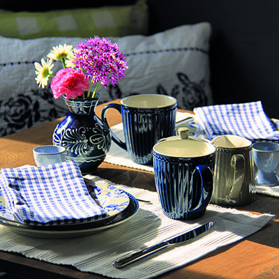 Gedeckter Tisch, Geschirr in blau gehalten mit frischen Blumen und blau karierten Servietten.