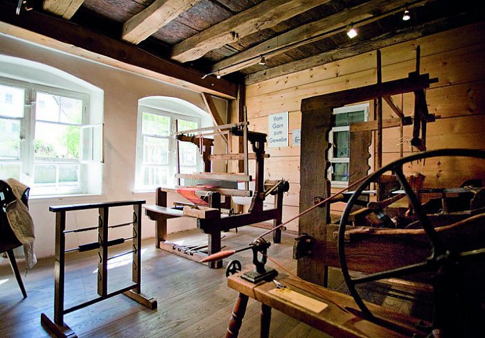 In einem Raum stehen alte Webstühle und Handwerkszeug von Weber.