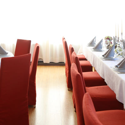 Elegant und festlich gedeckte Tische, um die rote Stühle stehen.