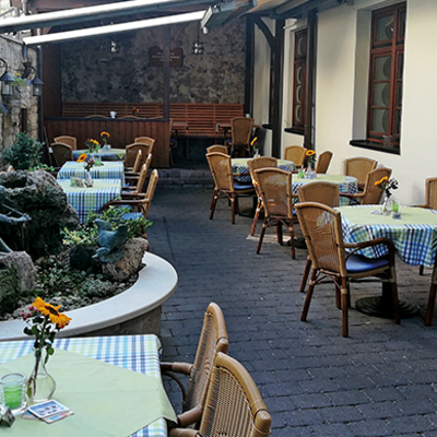 Restaurant Eberbacher Hof Außenbereich. Tische und Holzstühle. Ein kleiner Brunnen.